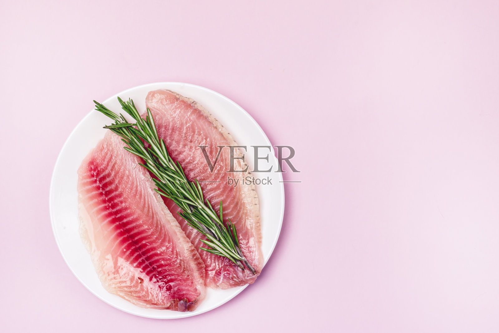 生罗非鱼片与迷迭香在白色盘子俯视图水平准备烹饪健康的食物照片摄影图片