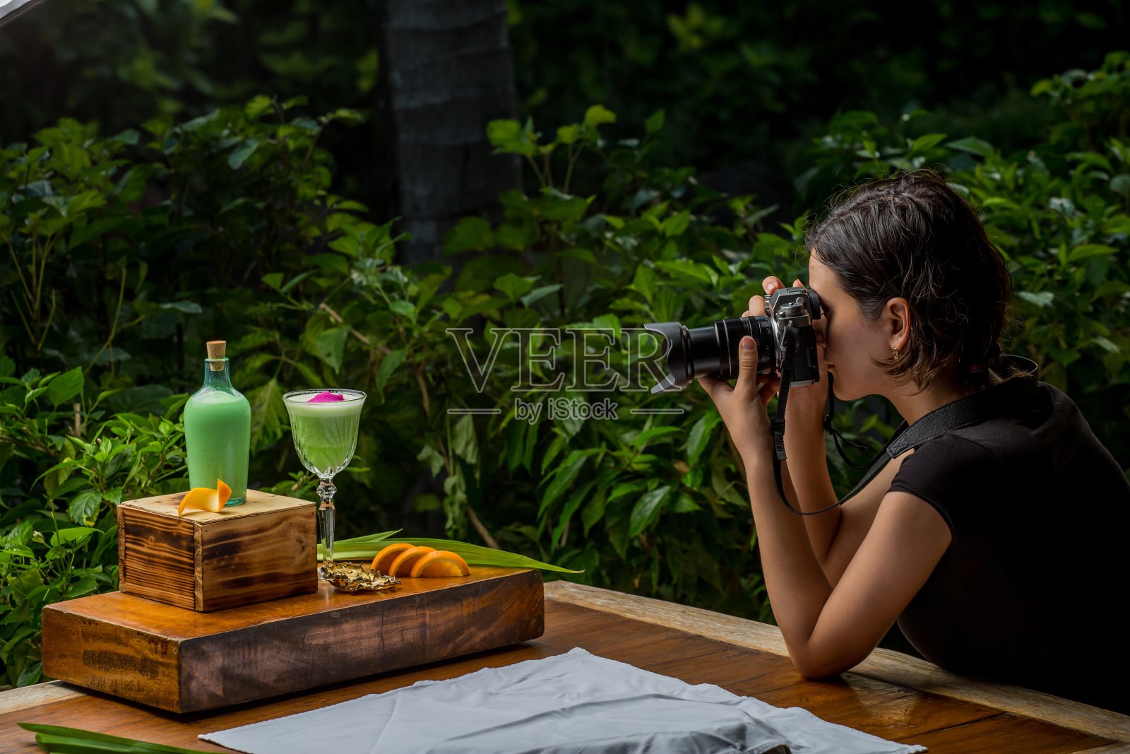 年轻女子用专业相机拍摄美食照片。专业的食物摄影师在餐厅拍摄照片摄影图片