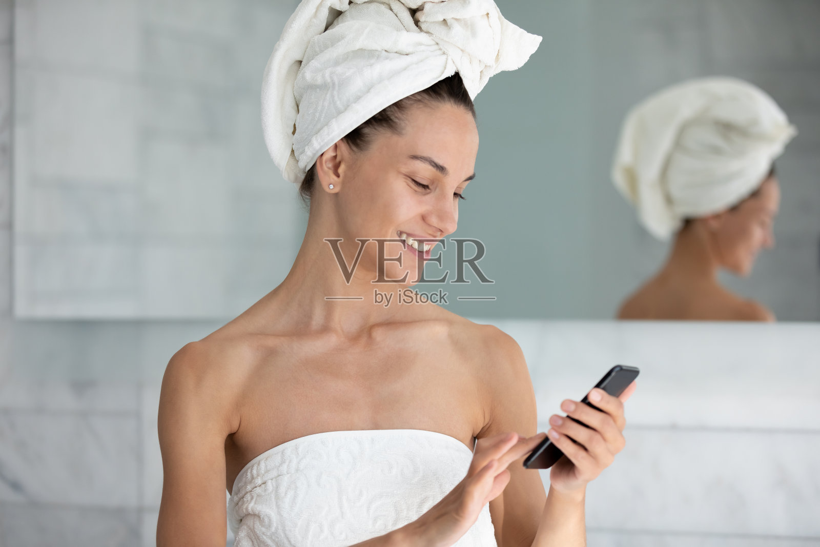 微笑的女人在现代浴室里使用智能手机照片摄影图片