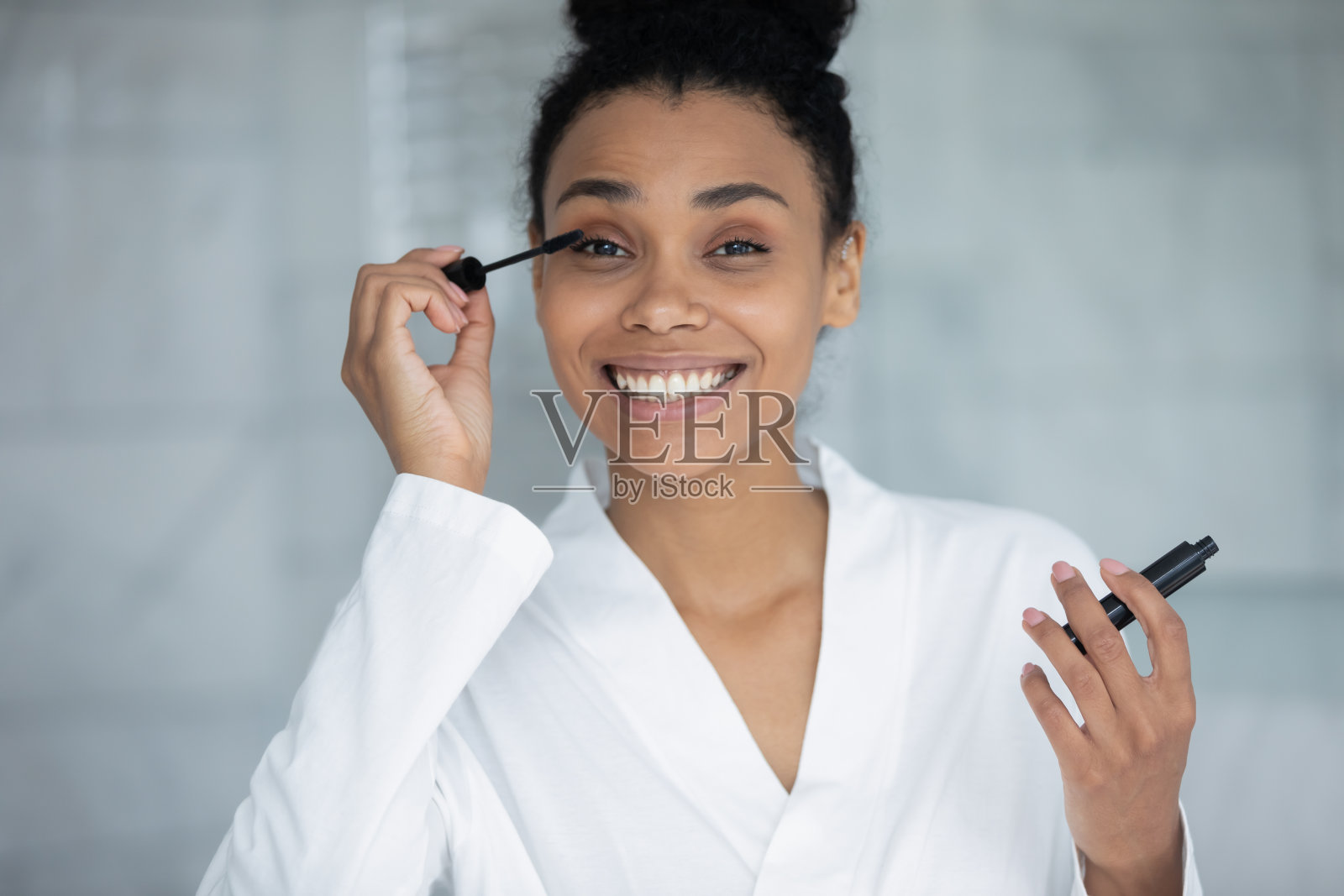 头像微笑的非洲裔美国妇女使用黑色睫毛膏照片摄影图片