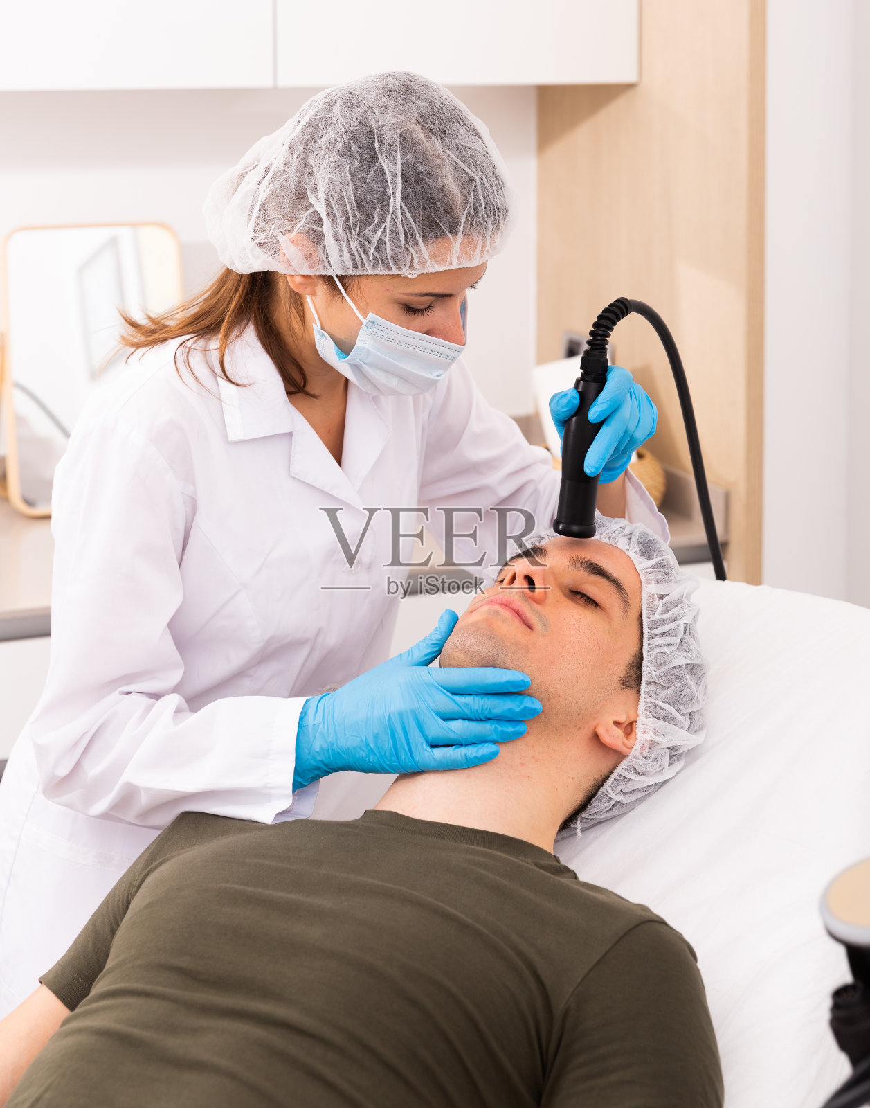 女性美容师为男性进行面部无针光疗法照片摄影图片