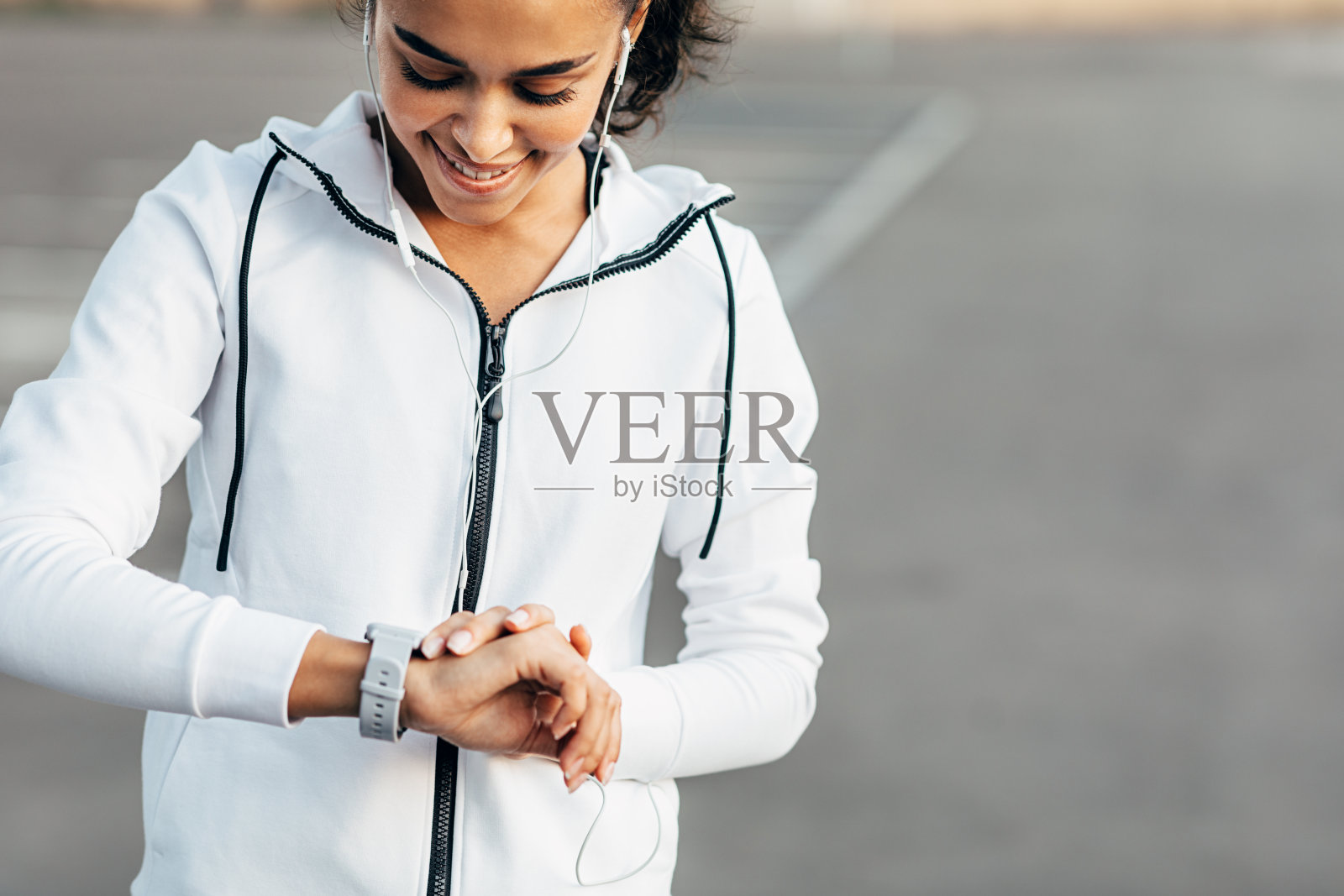 一名年轻女子在训练中一边听音乐一边用智能手表查看自己的活动情况。照片摄影图片