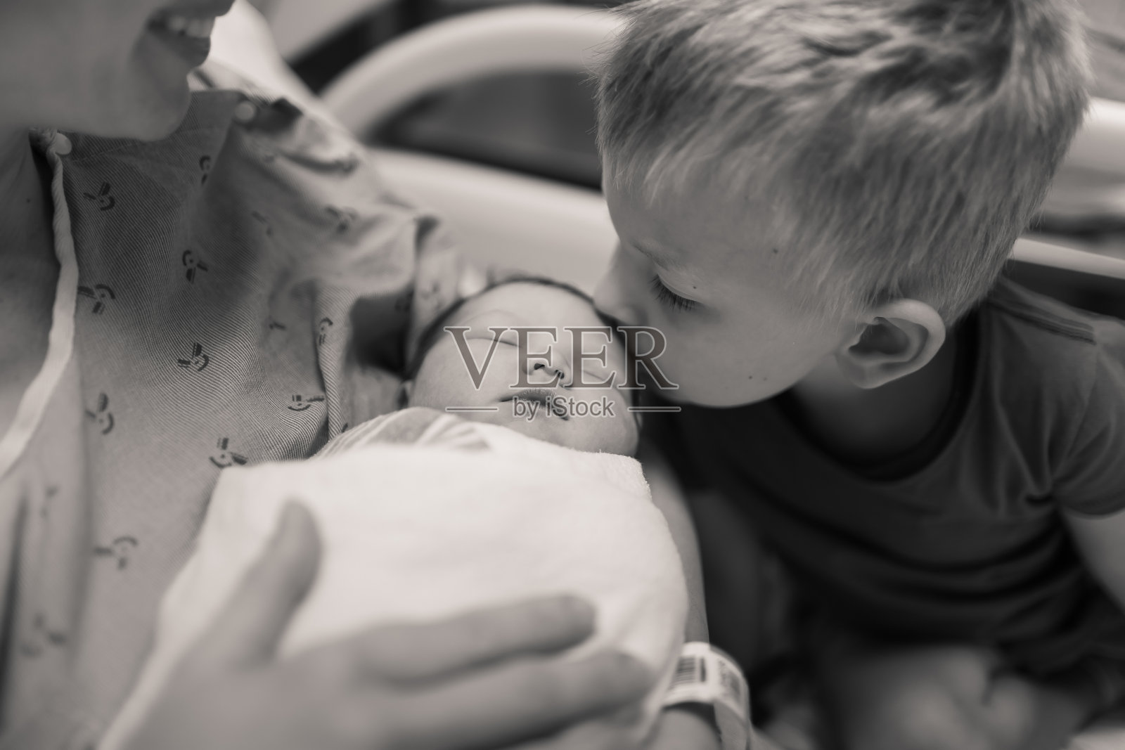 小弟弟在医院亲吻他刚出生的小妹妹。幸福的家庭。照片摄影图片
