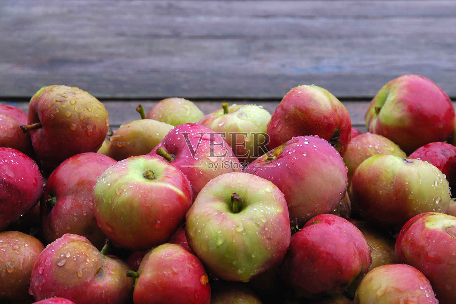 食物背景的小红苹果堆湿的雨水对木制的背景。选择重点，自然季节性水果，秋收照片摄影图片