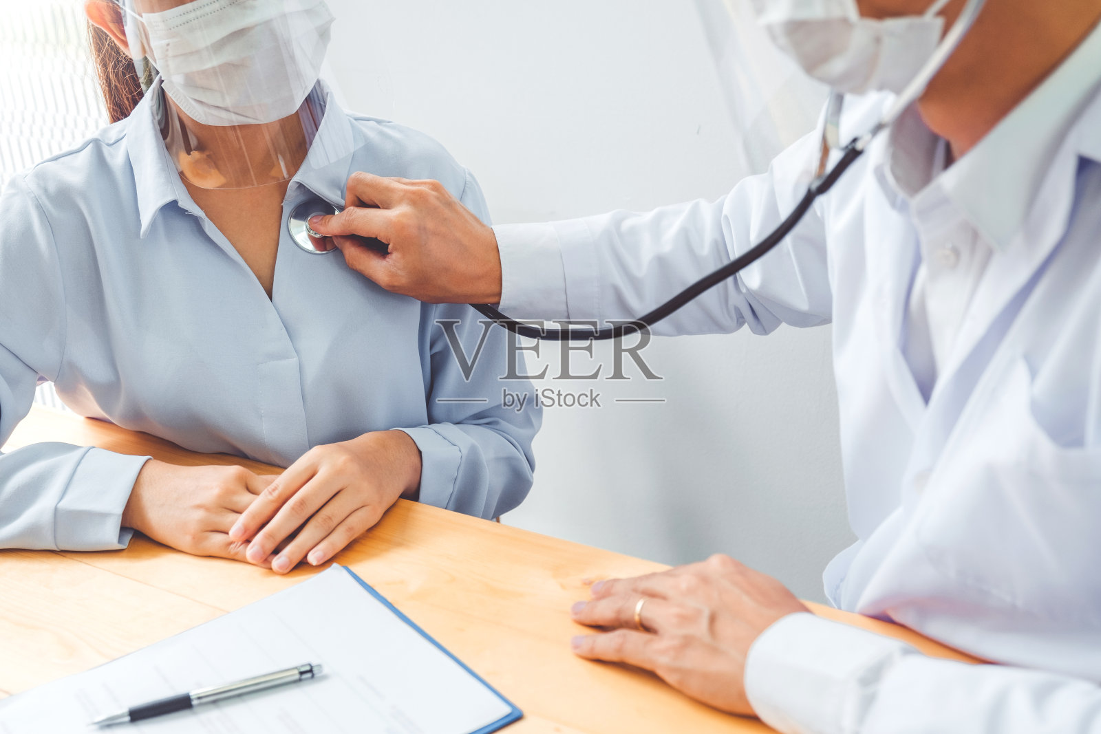 冠状病毒流行后，医生戴口罩和眼镜测量妇女的动脉血压在护理病房帮助，鼓励和同情。照片摄影图片