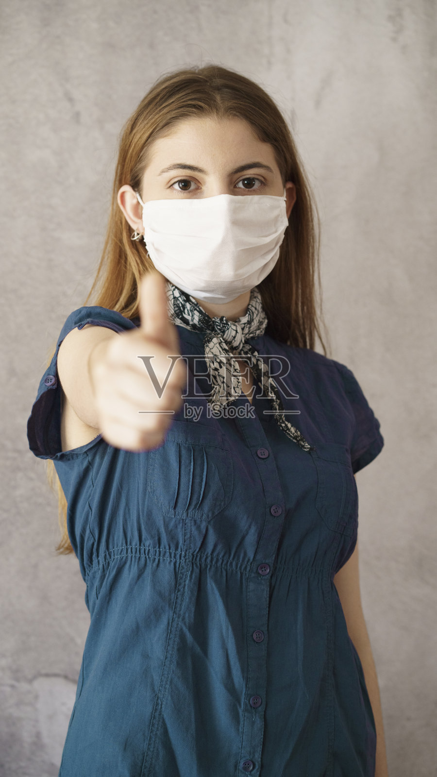 一名年轻女子戴着防护面罩，翘起大拇指照片摄影图片