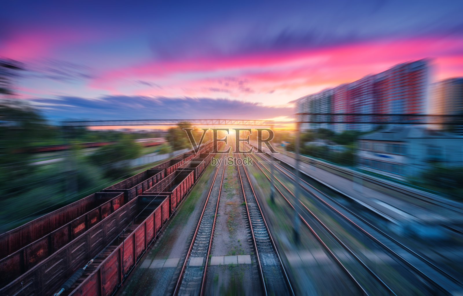 铁路鸟瞰图和彩色天空与云彩日落与运动模糊效果在夏季。工业景观以货运列车、火车站为背景模糊。铁路平台照片摄影图片