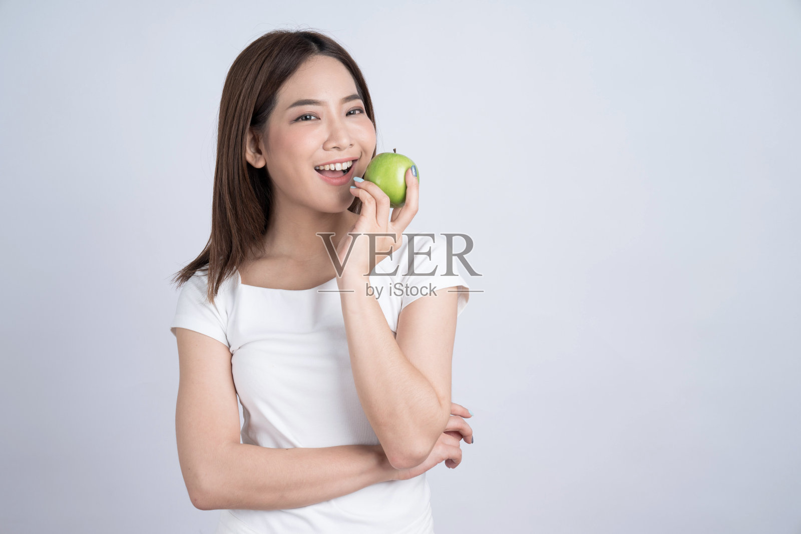 年轻的亚洲幸福微笑的女人与绿色的苹果，孤立在白色的背景。照片摄影图片