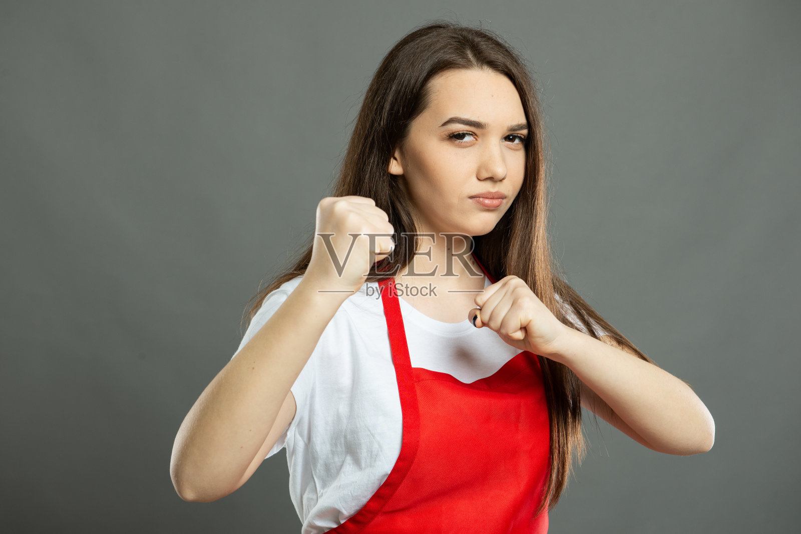年轻的女超市员工展示拳头看起来很疯狂的肖像照片摄影图片