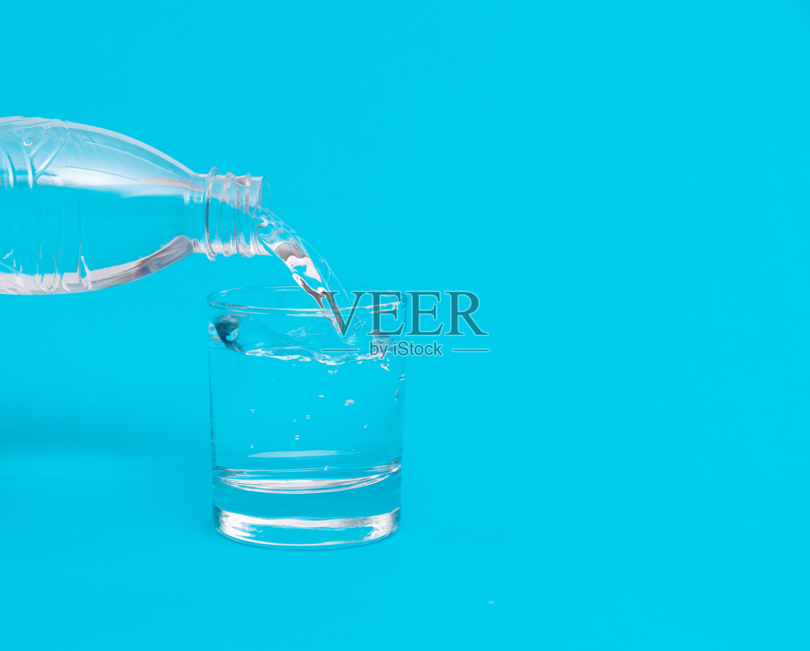 一瓶水倒进一个玻璃杯里照片摄影图片