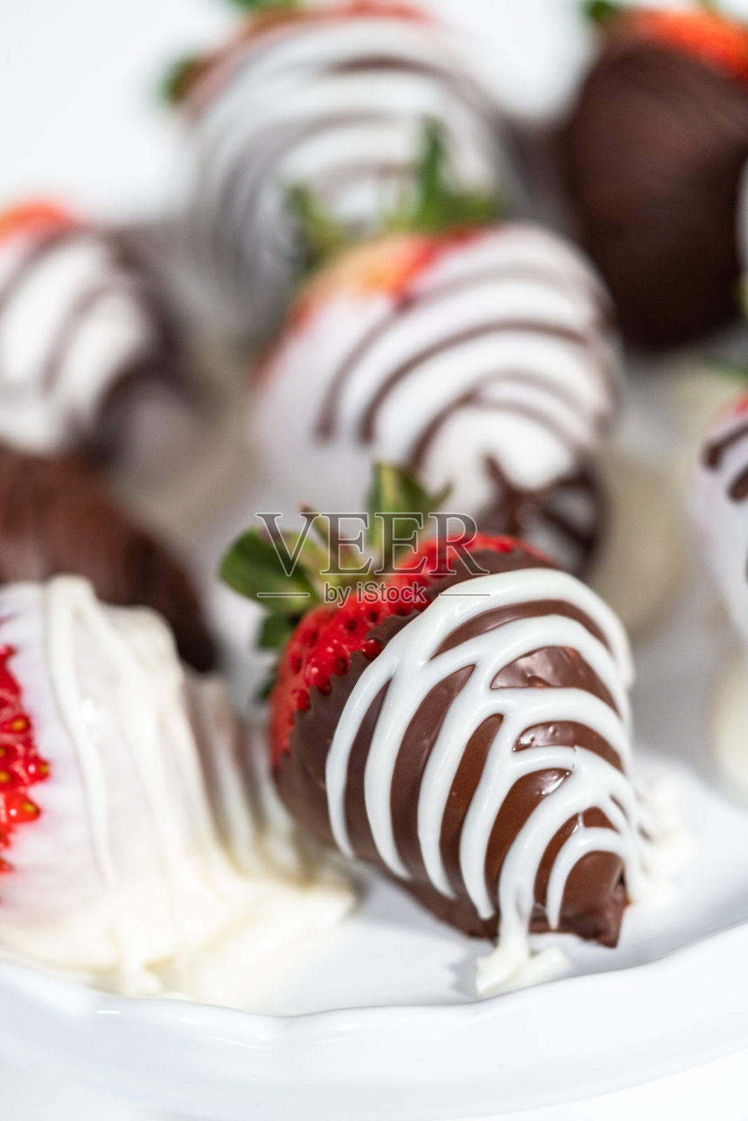 白巧克力和黑巧克力蘸草莓放在白色蛋糕架上。照片摄影图片