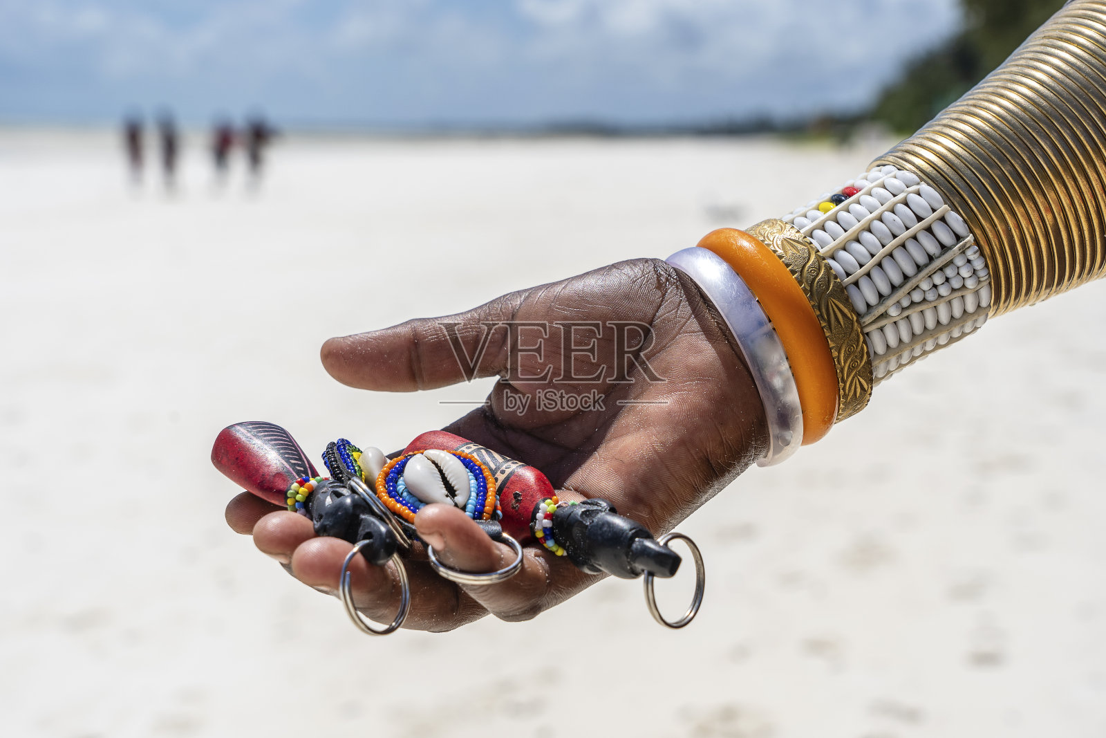 在非洲坦桑尼亚的桑给巴尔岛上，马赛部落女性的手拿着一个彩色手镯，里面有纪念品出售给游客。旅游度假概念照片摄影图片