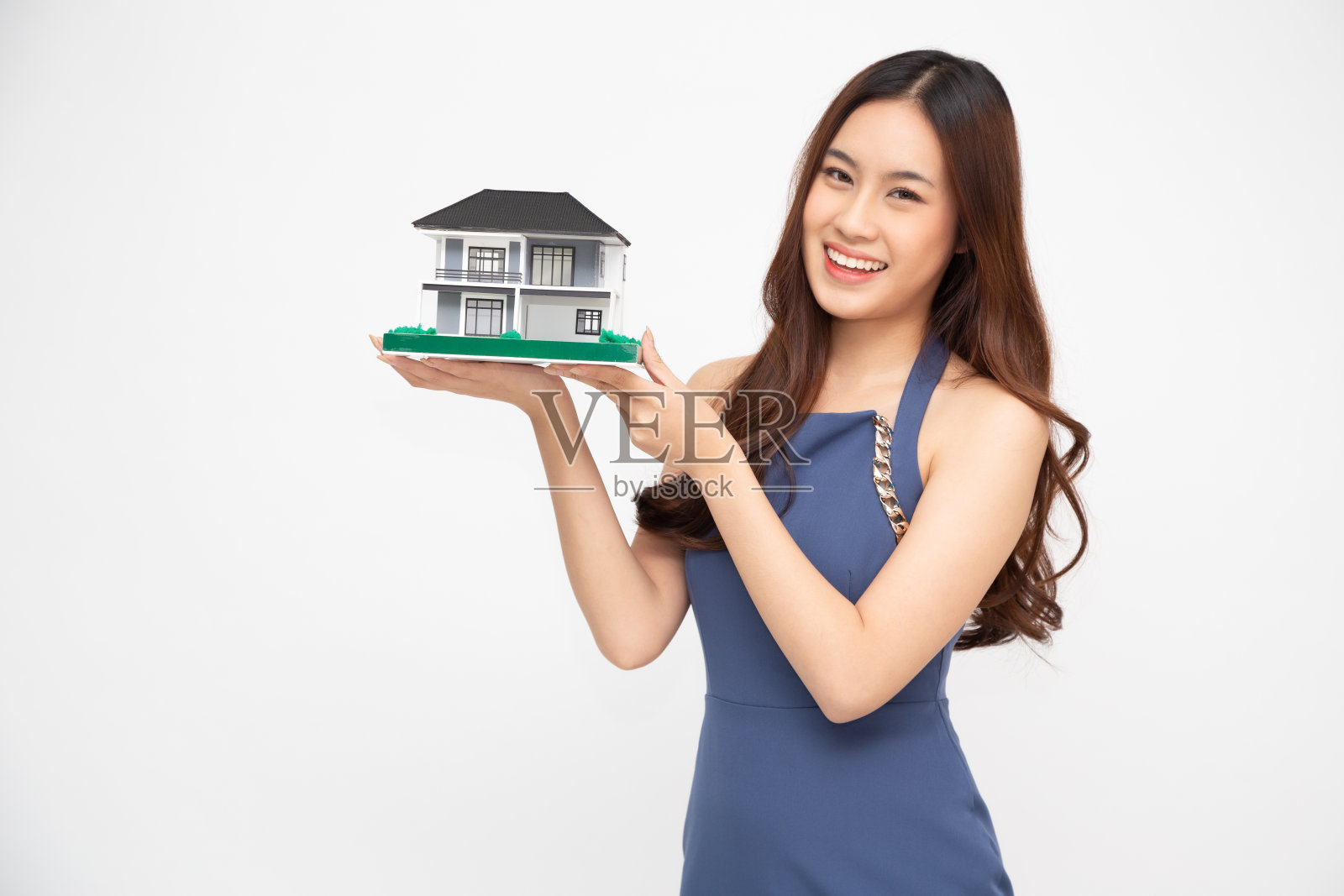 年轻的亚洲女人微笑着，拿着房子样本模型孤立的白色背景，房地产和家庭保险的概念照片摄影图片