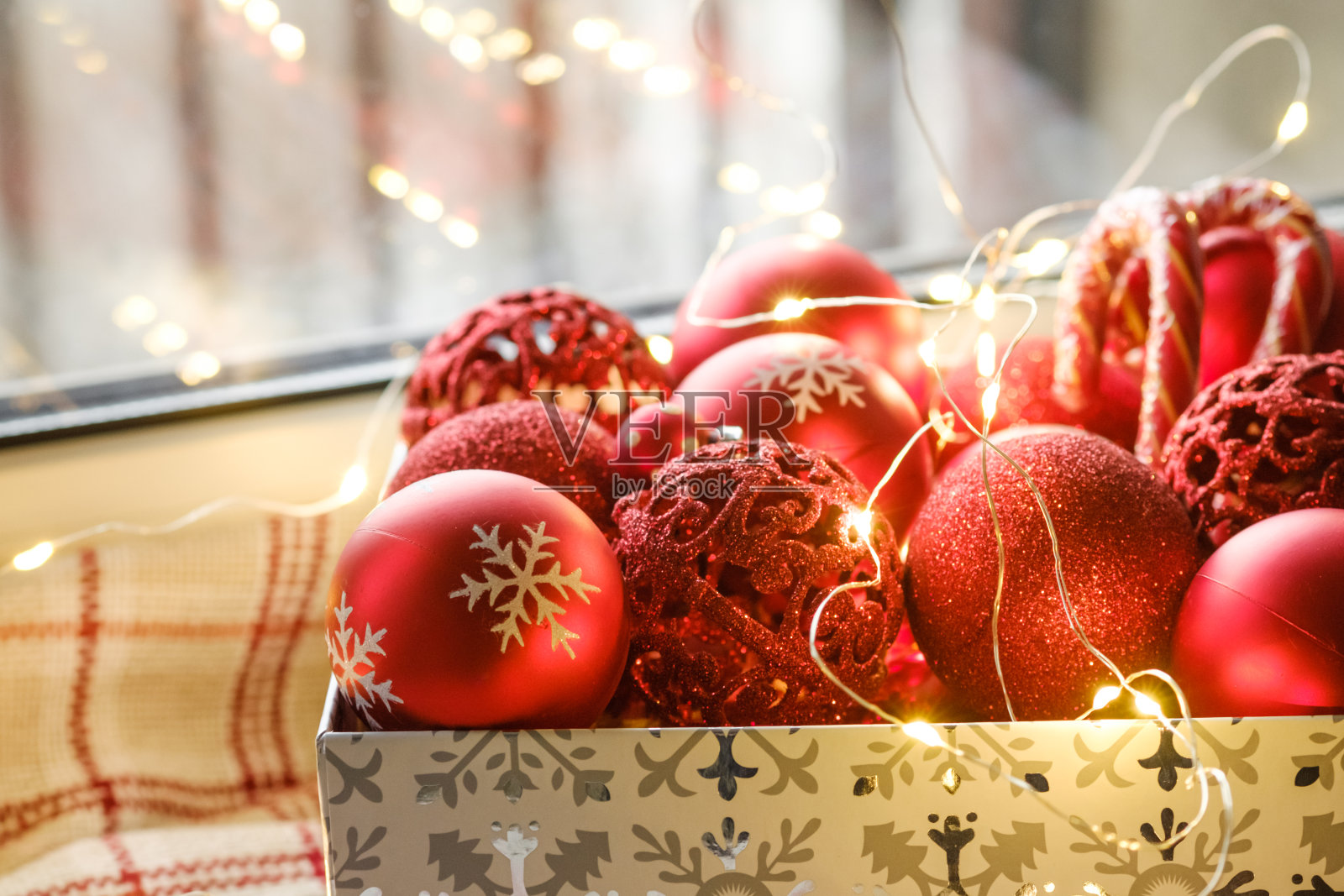 红色的圣诞树玩具在一个盒子里，准备装饰圣诞树。圣诞卡与圣诞灯和装饰品。有选择性的重点。照片摄影图片