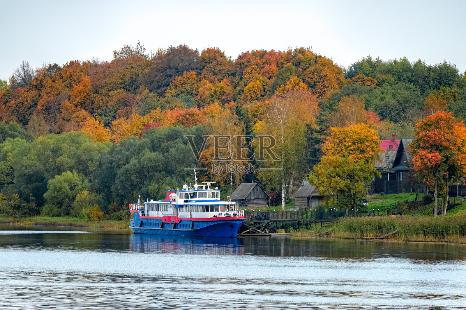 在一个朦胧的秋天的早晨，一艘古老的旅游休闲摩托艇停泊在沃尔科夫河岸边的码头上照片摄影图片