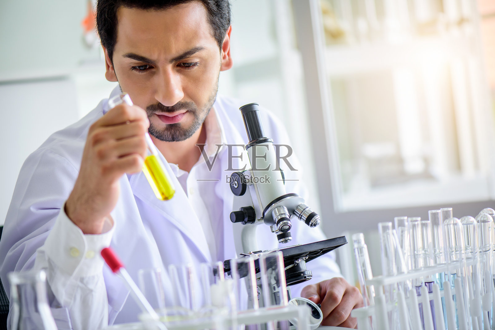 有吸引力的快乐科学家男人实验室技术员助理在实验室用显微镜在试管中分析样品。医学、制药和科研开发理念。照片摄影图片
