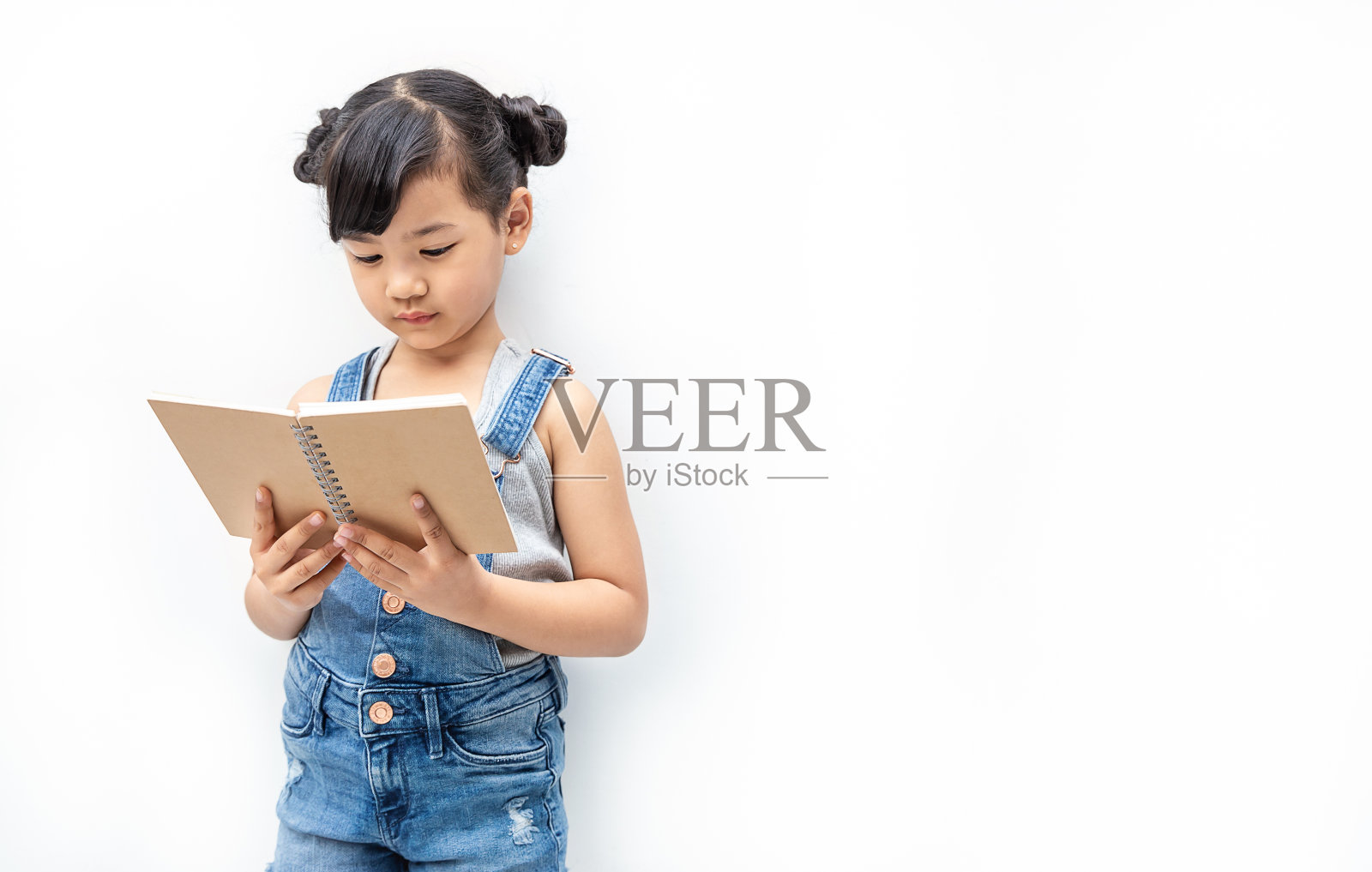 可爱的亚洲幼童女孩的肖像阅读书孤立在白色的背景，教育知识。宅女读书读书，在家上学又回到学校的概念照片摄影图片