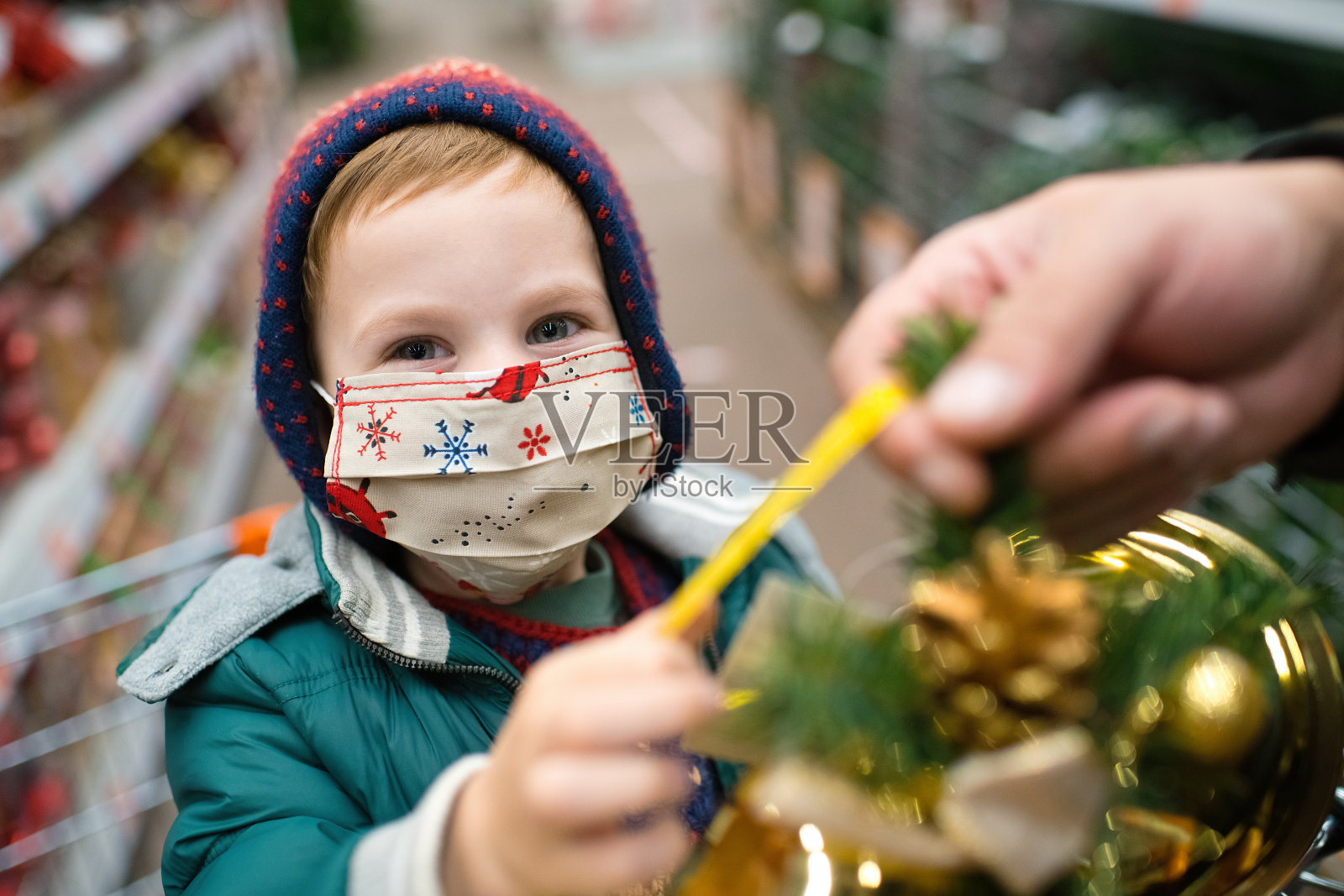可爱的小男孩戴着防护口罩在商店挑选圣诞装饰品照片摄影图片