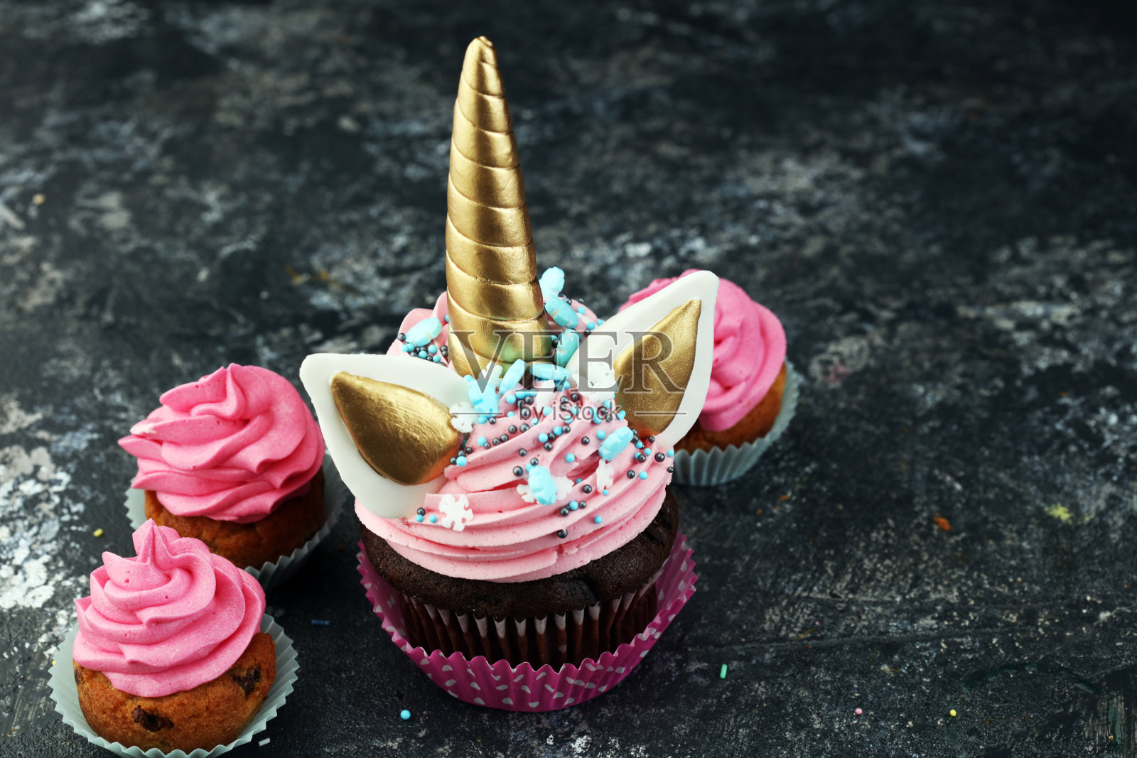 独角兽纸杯蛋糕上装饰着五颜六色的奶油糖霜和糖屑照片摄影图片