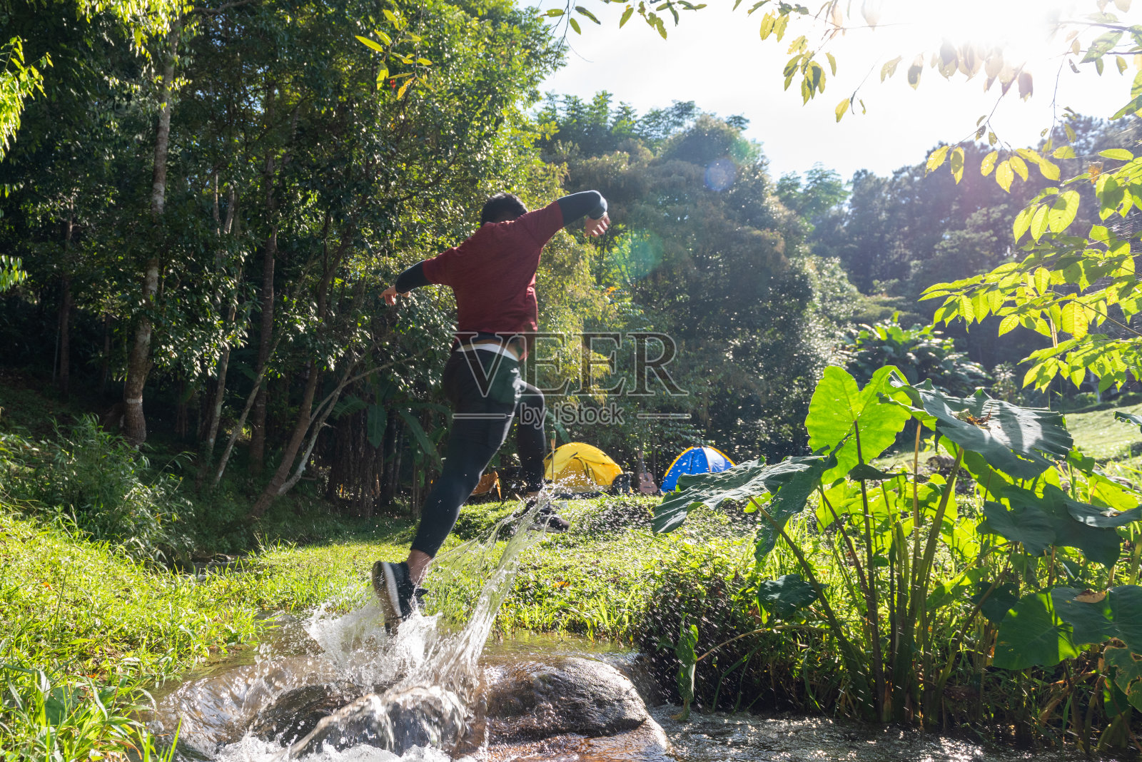 低角度的强壮亚洲男子运动员在运动服跑过水在森林山径在夏天的一天。健康的户外生活方式，假期和运动训练的理念。照片摄影图片