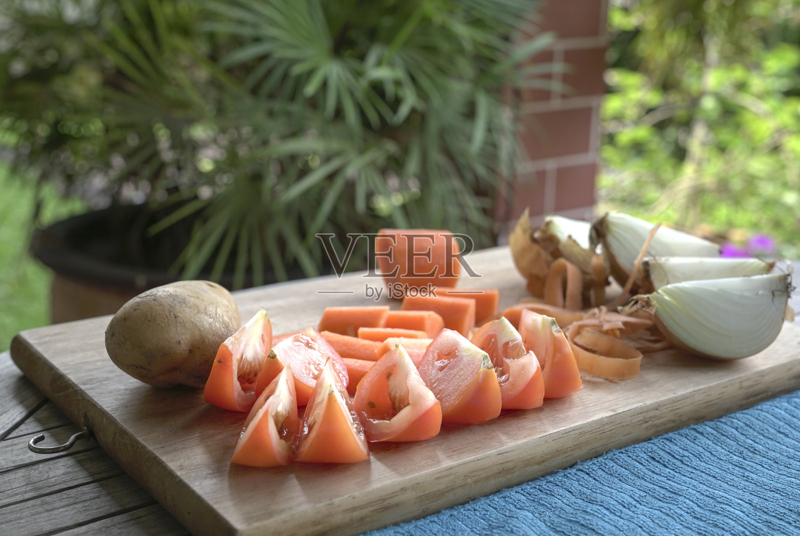 把西红柿、胡萝卜、洋葱和土豆切在木板上。为健康的一餐做准备。照片摄影图片