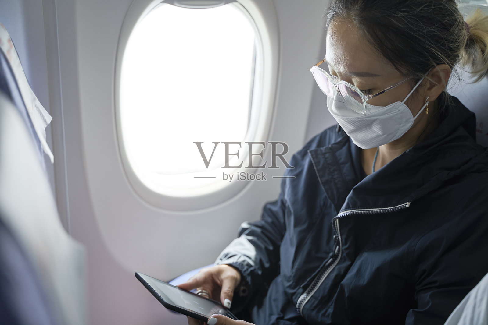 亚洲女性在飞机上使用电子阅读器阅读照片摄影图片