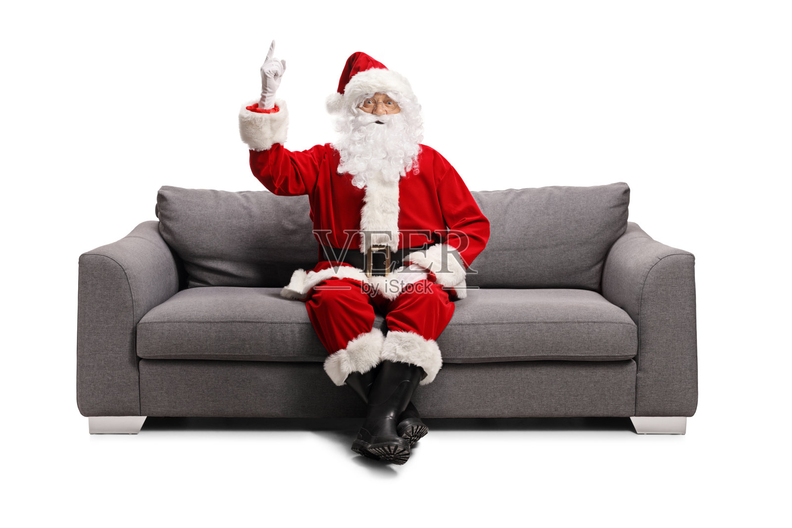 圣诞老人坐在灰色的沙发上，指着上面照片摄影图片