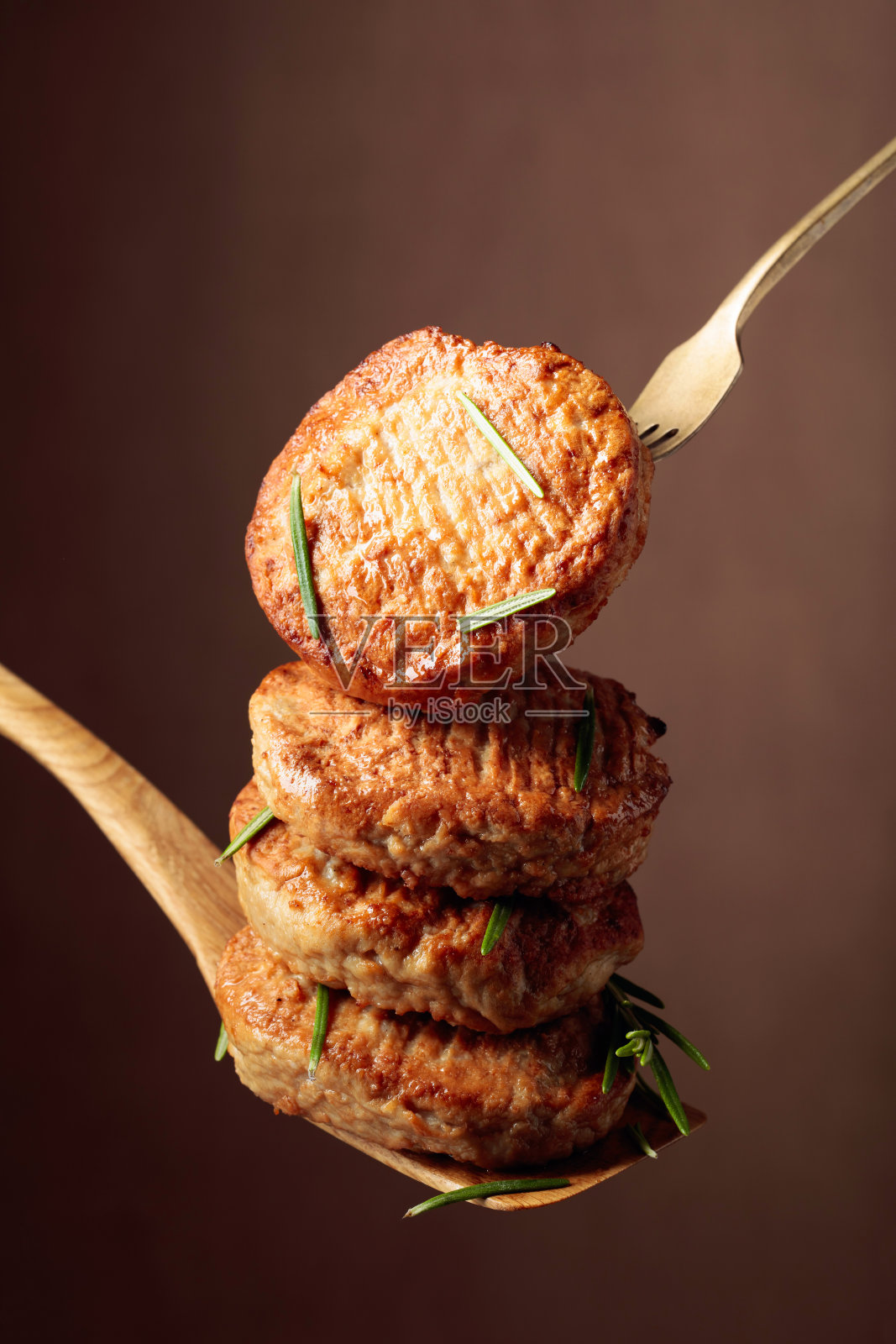 美味的自制肉片配迷迭香在棕色的背景上。照片摄影图片