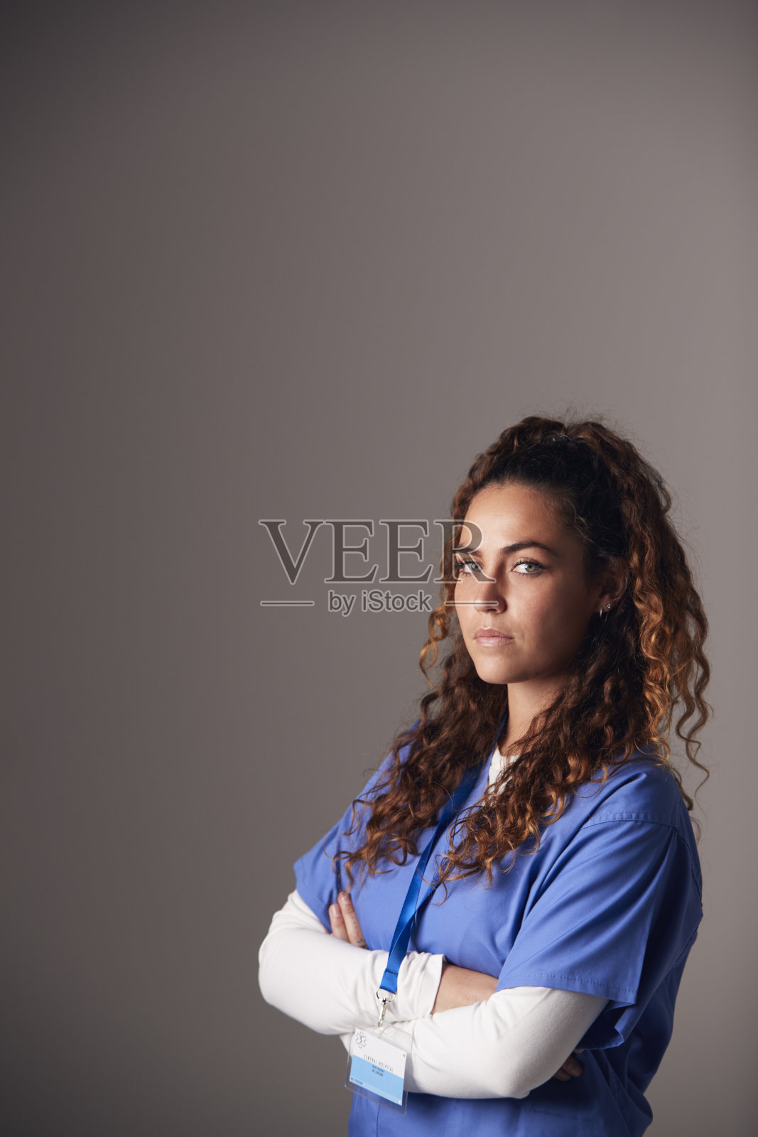 年轻女护士穿着手术服站在灰色背景下的工作室肖像照片摄影图片