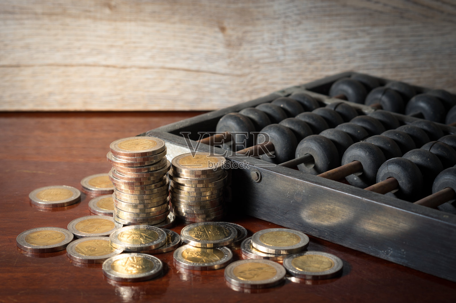 钱的硬币和旧木算盘在桌子上。照片摄影图片