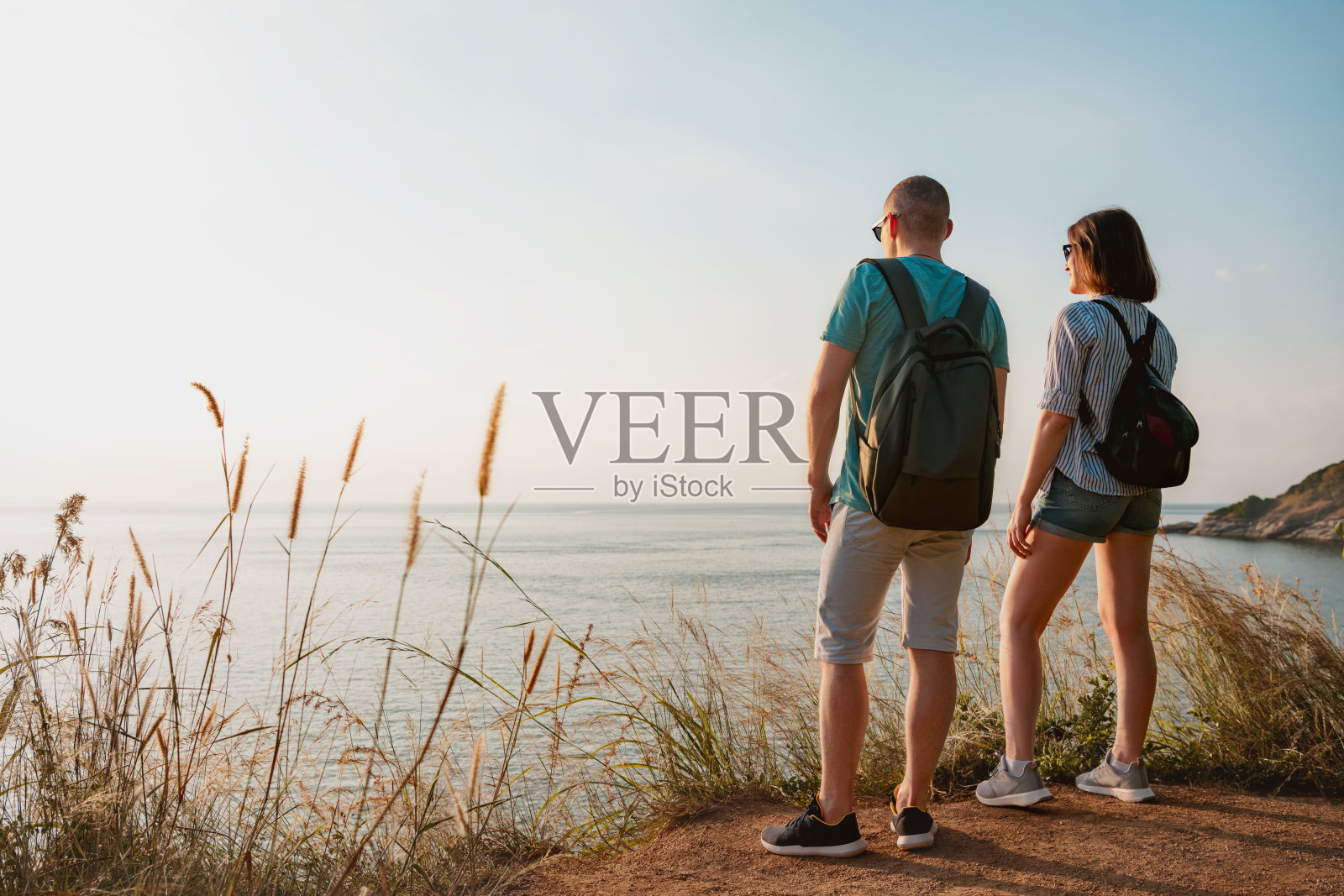 两名徒步旅行者站在日落海景点照片摄影图片
