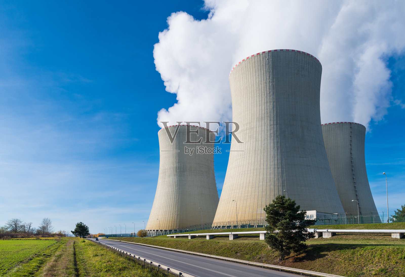 核电站双曲面冷却塔与水蒸汽羽状物在蓝天背景照片摄影图片
