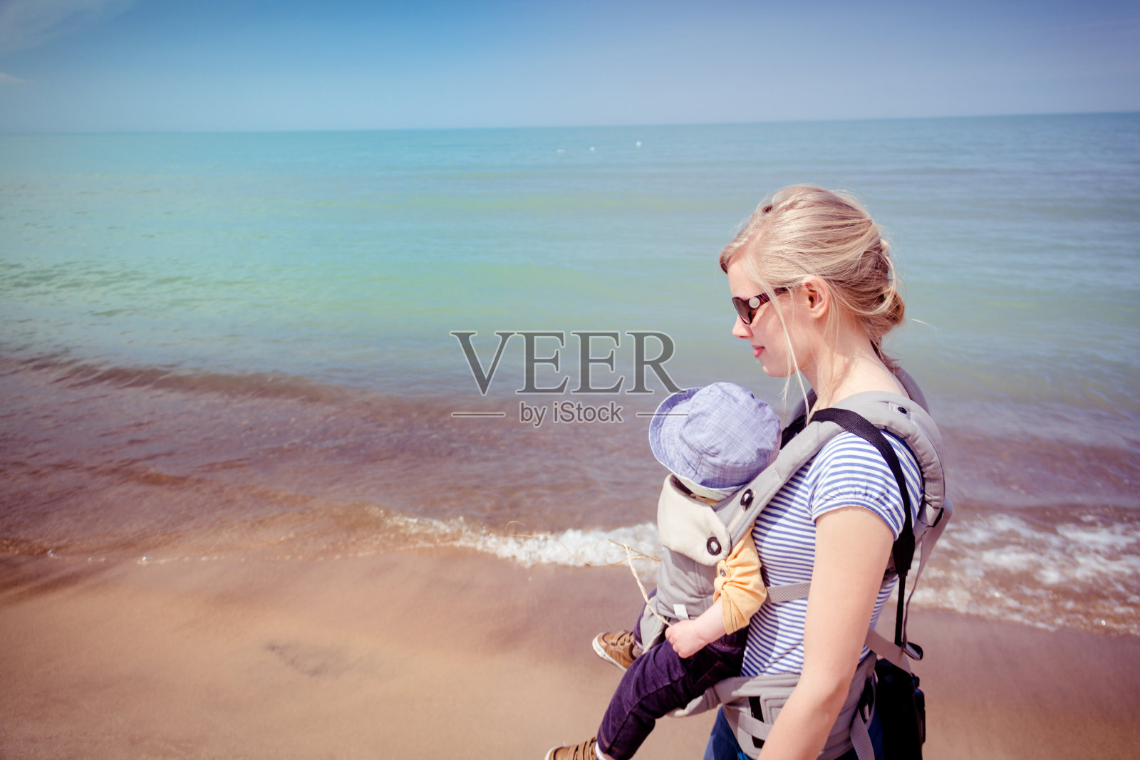 母亲抱着婴儿沿着印第安纳沙丘国家公园的海滩照片摄影图片