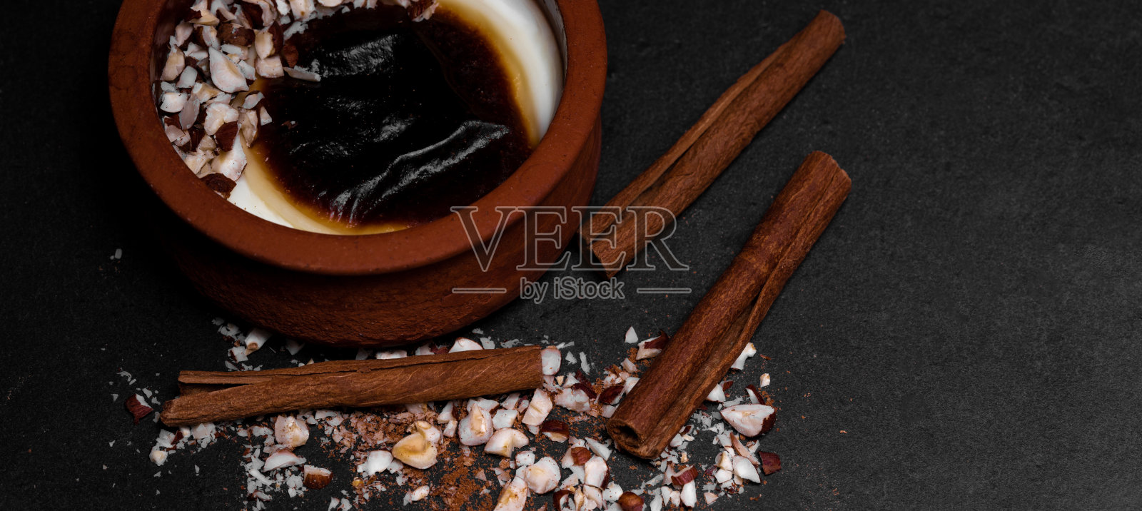 土耳其传统的砂锅甜点与肉桂棒和榛子;sutlac。烤米饭布丁。照片摄影图片