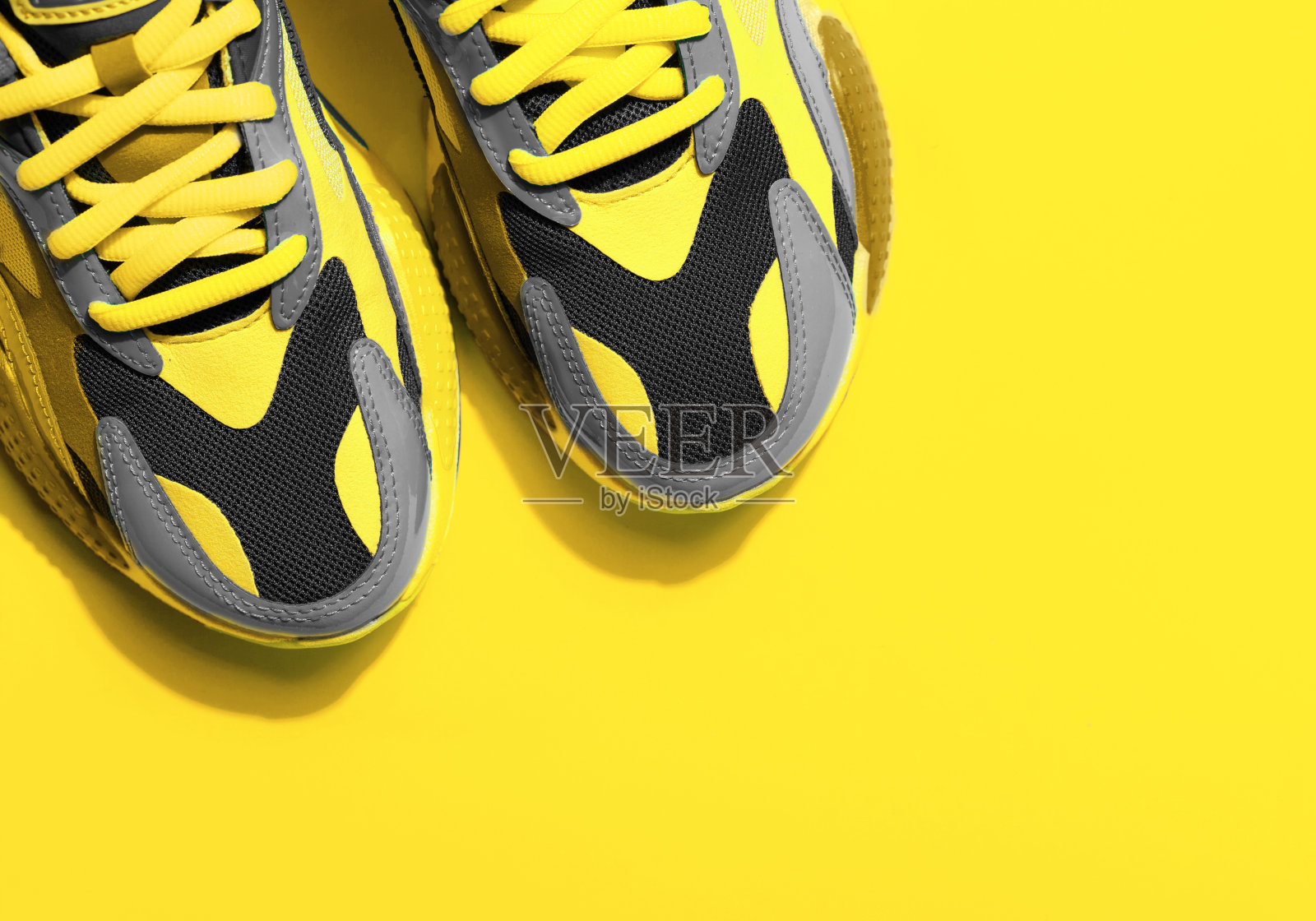 多色运动鞋在黄色背景与阴影照片摄影图片