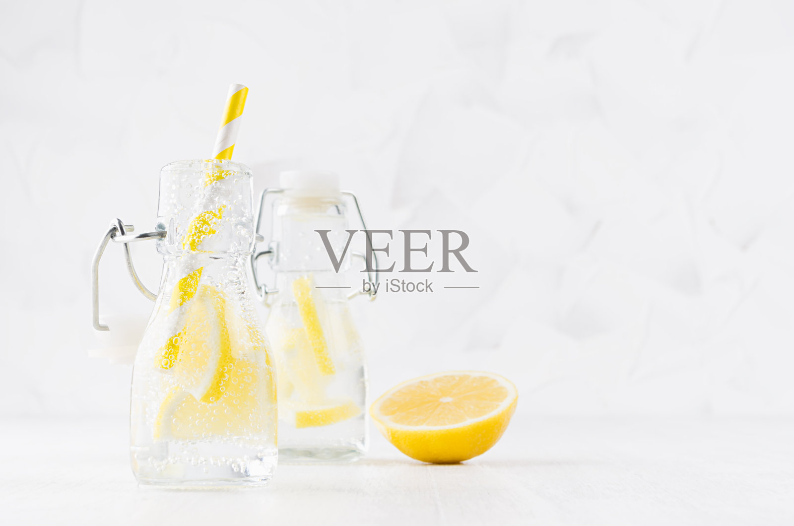 冷鲜水果柑橘饮料与黄色柠檬苏打水，气泡，有趣条纹吸管在简单柔和明亮的白色背景，复制空间。照片摄影图片