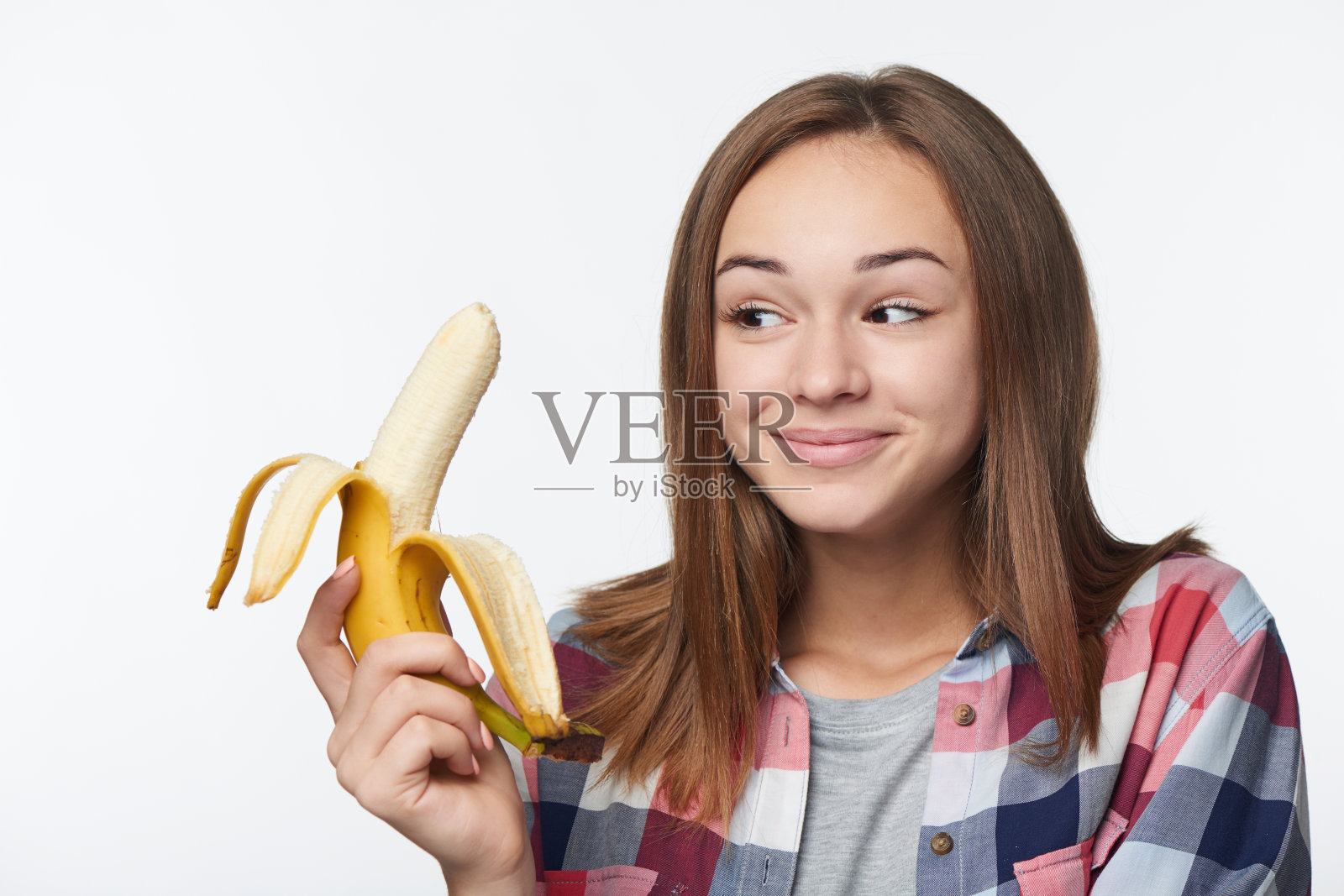 一个十几岁的女孩拿着半剥了皮的香蕉的肖像照片摄影图片