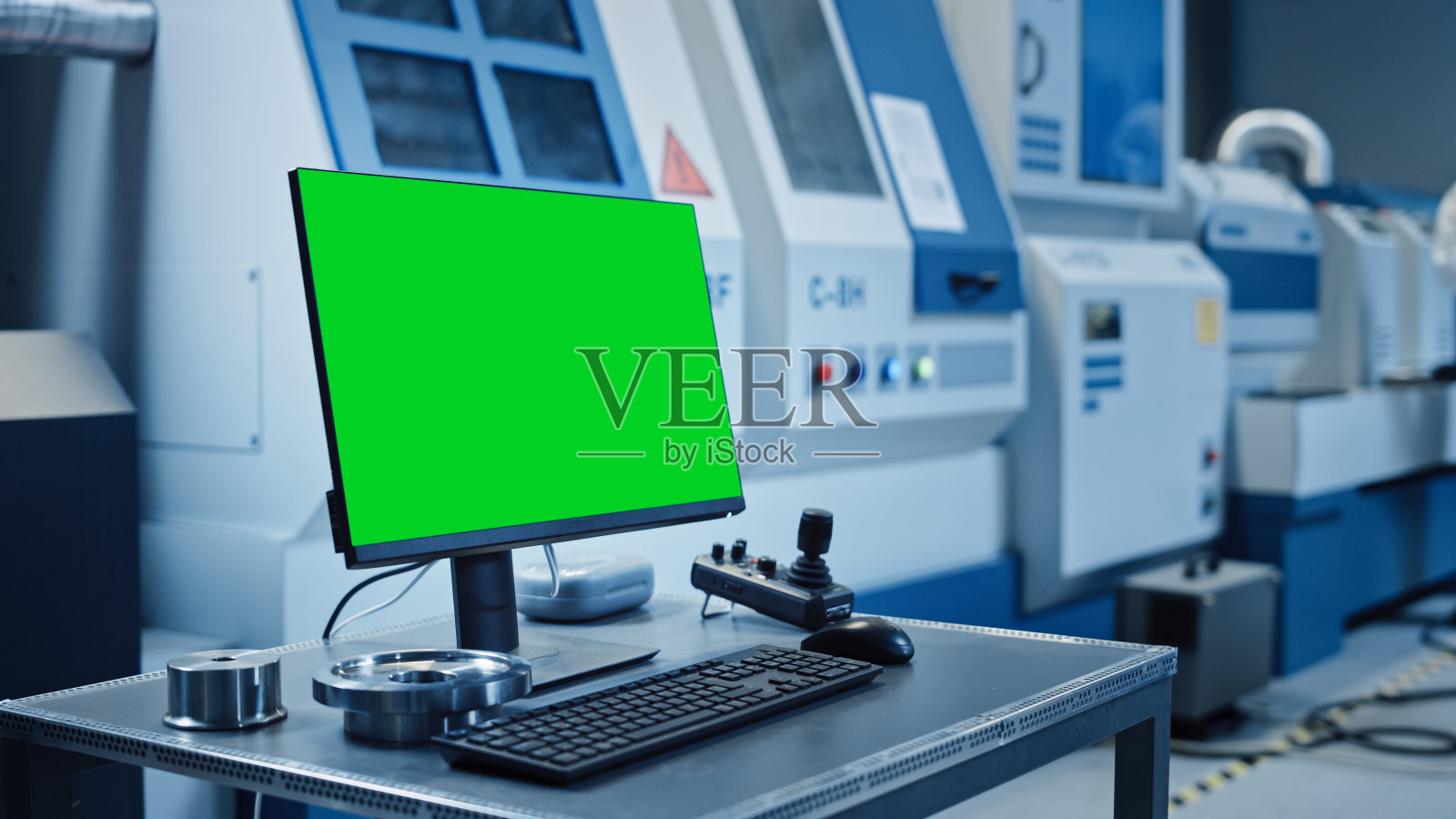 工厂洁净室:在桌面个人电脑上显示绿色屏幕色度键显示。在数控机械背景下，专业人员在生产线上使用机器人手臂。照片摄影图片