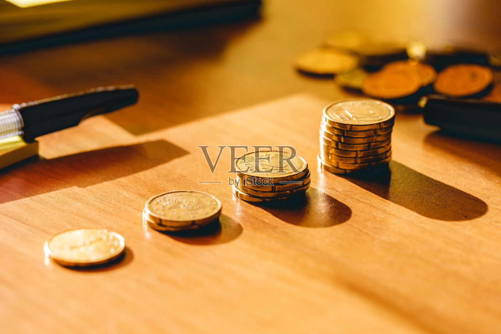 桌子上的欧元硬币堆被阳光照亮，周围是会计物品照片摄影图片