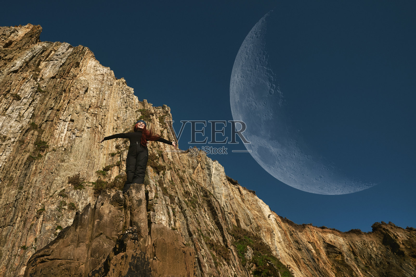 一个女人和月亮在悬崖上摆姿势照片摄影图片