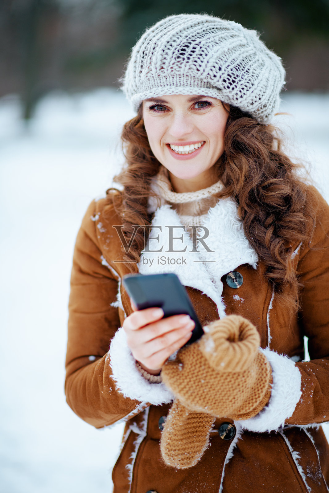 冬天在城市公园外面使用手机应用程序的女人照片摄影图片