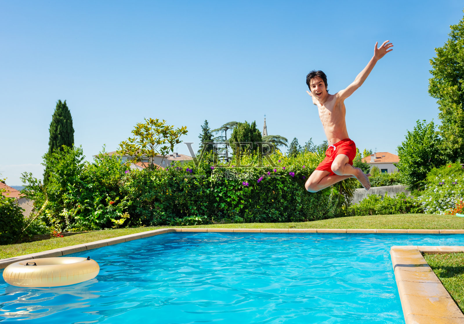 一个十几岁的男孩跳进游泳池的水里照片摄影图片