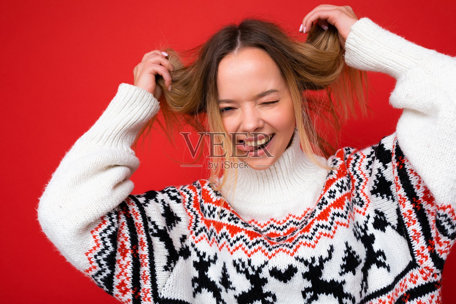 照片拍摄的年轻美丽疯狂疯狂有趣快乐的金发女人穿着冬季毛衣孤立在红色背景与复制空间照片摄影图片