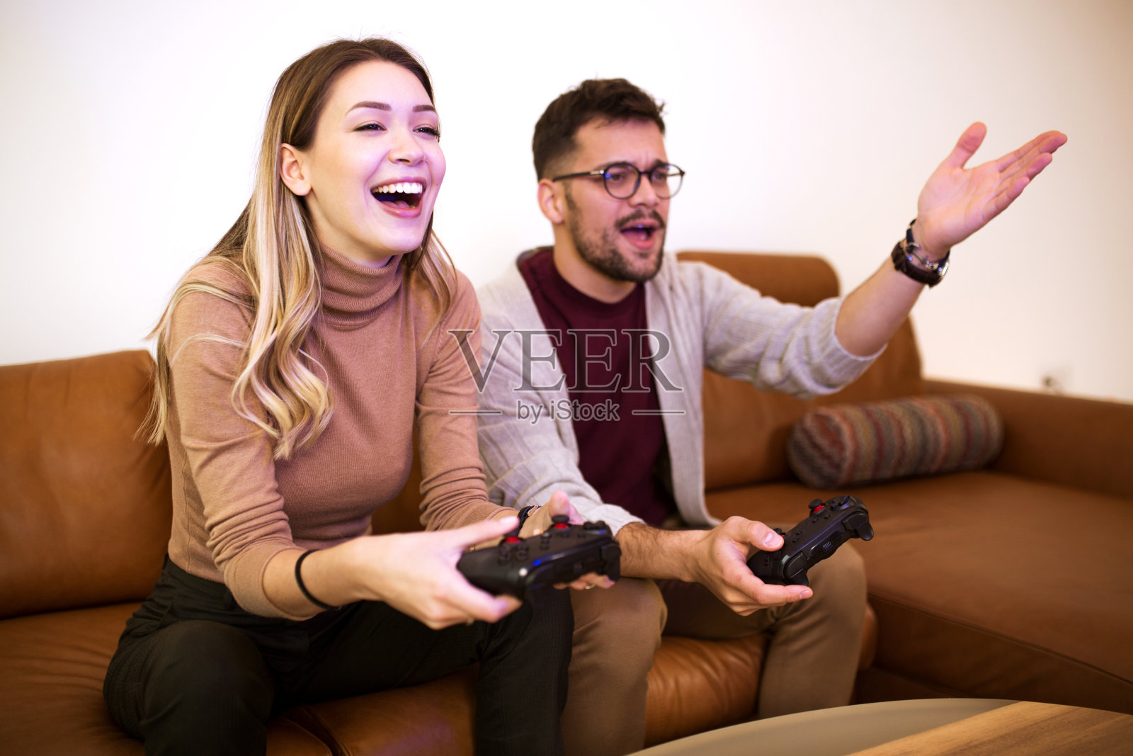 一对年轻夫妇坐在客厅的沙发上玩电子游戏照片摄影图片