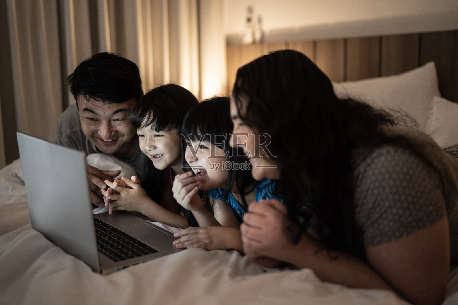 幸福的家庭躺在床上用电子平板电脑看东西照片摄影图片