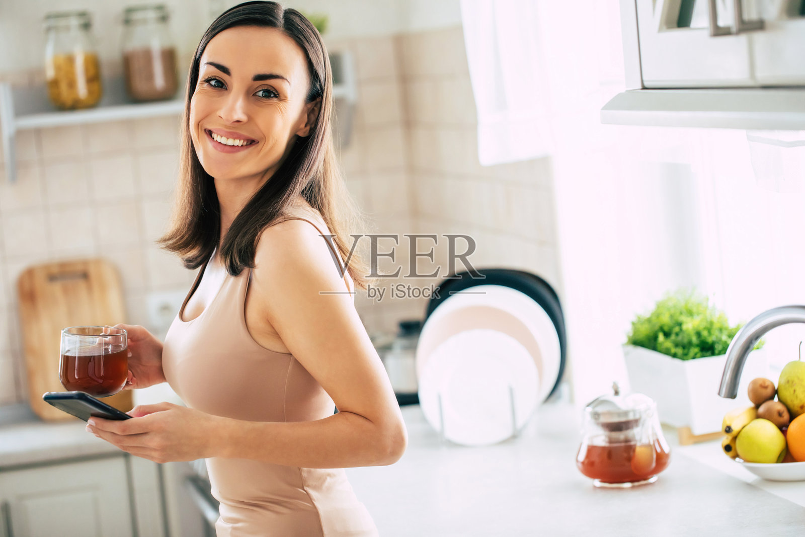 美丽的微笑年轻的黑发女人喝美妙的咖啡和放松在家庭厨房在周末照片摄影图片