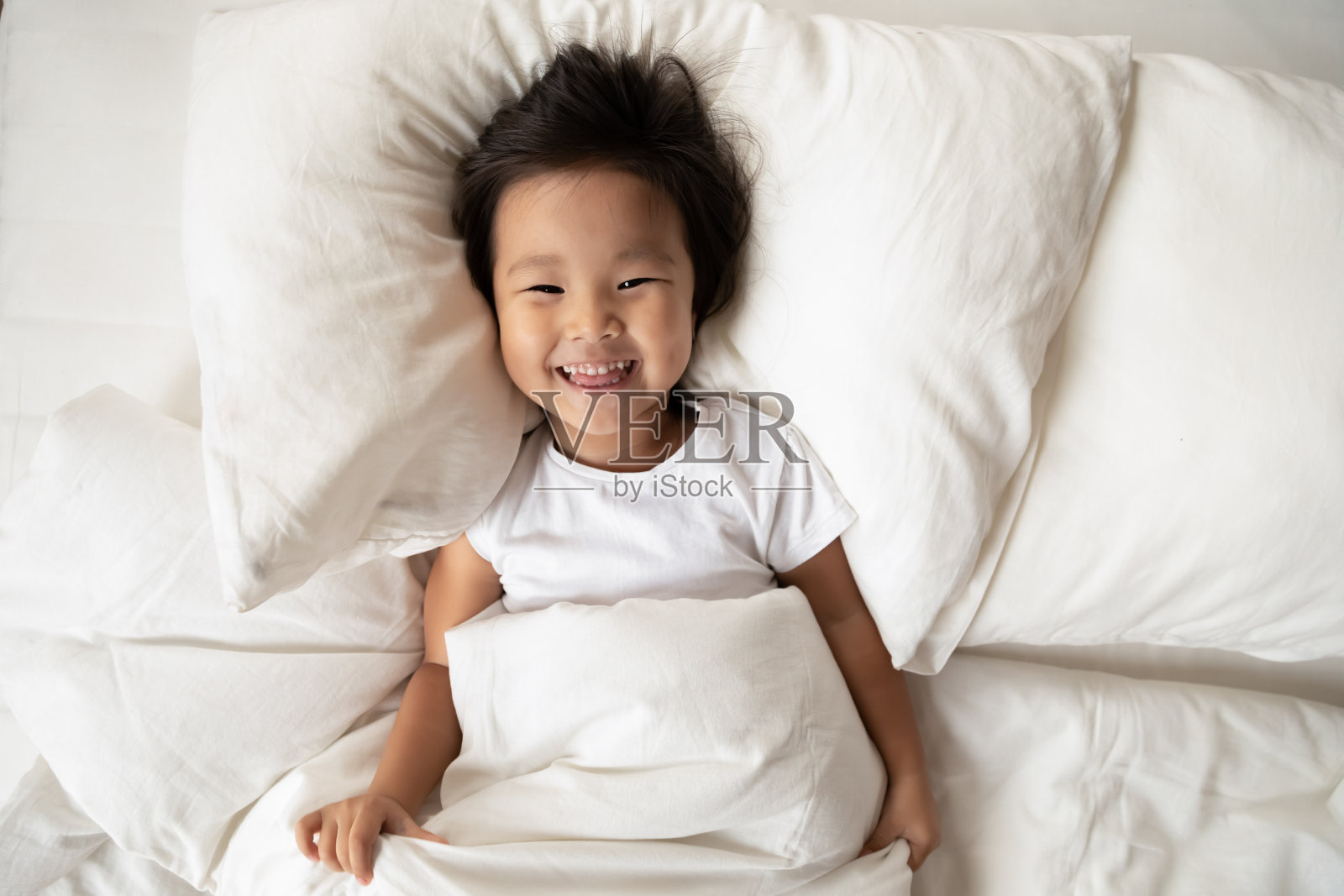 俯视图肖像微笑可爱的亚洲小女孩在床上照片摄影图片