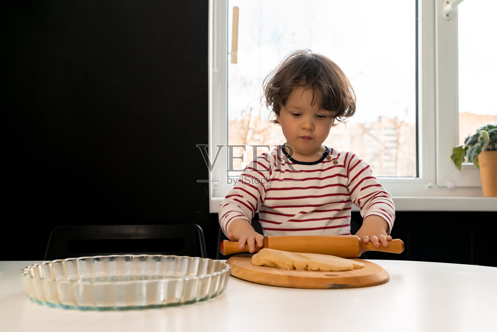 小孩正在准备蛋糕，用擀面杖在餐桌上擀面照片摄影图片