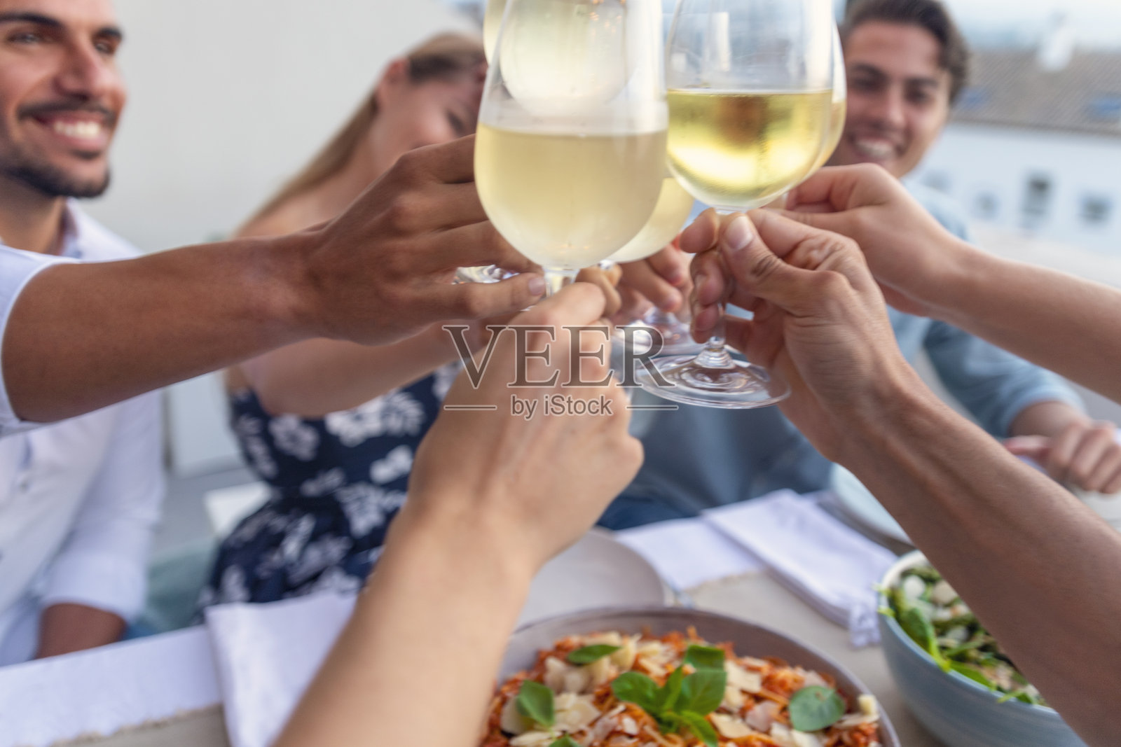 晚餐前，一群人用白葡萄酒敬酒。照片摄影图片
