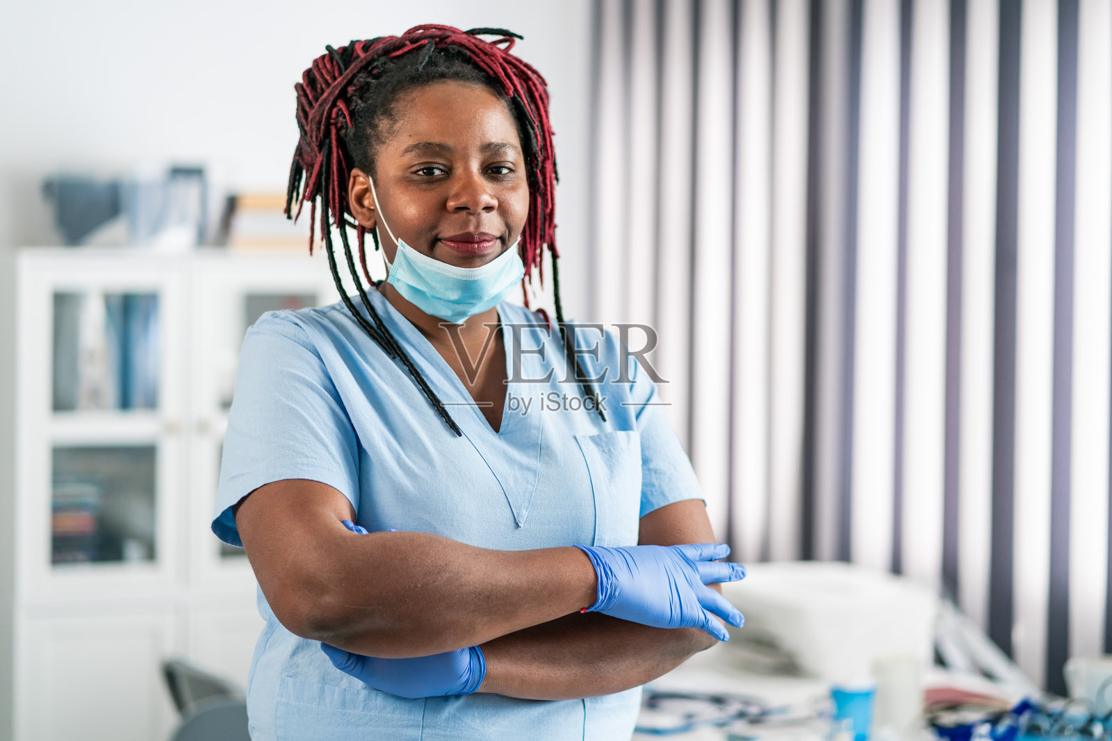 冠状病毒疫情期间，中年非洲裔女医生双臂交叉站在医生的办公室里照片摄影图片